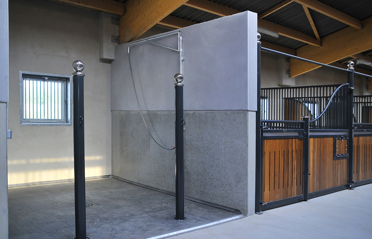 cement area for washing horses next to timber and steel stable panels, with black steel posts and metal ball detail