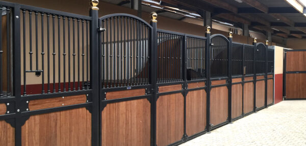 windsor internal stable panels with ornate gold balls on top of each gate and paved flooring