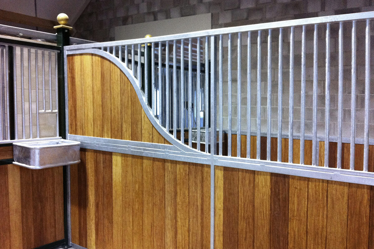 timber and steel stall divider in a stable with metal feed box
